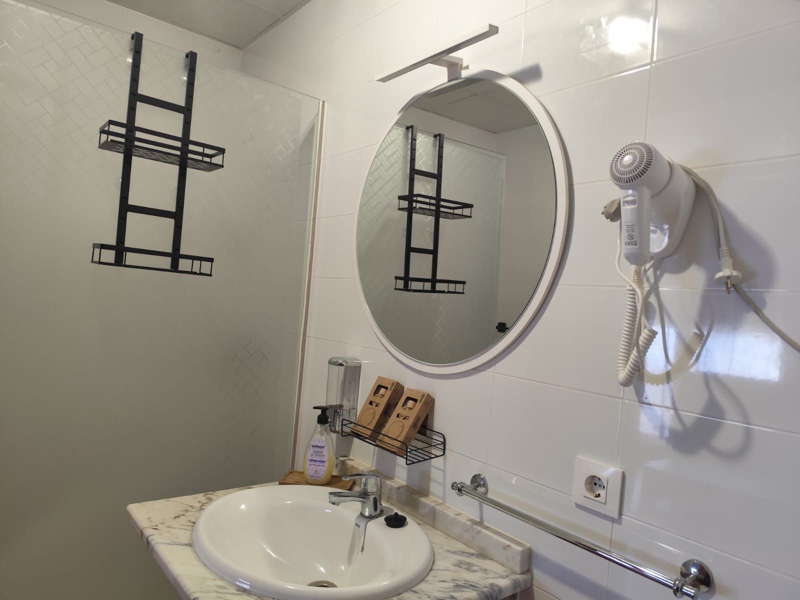 Un baño con lavabo, espejo y secador de pelo.