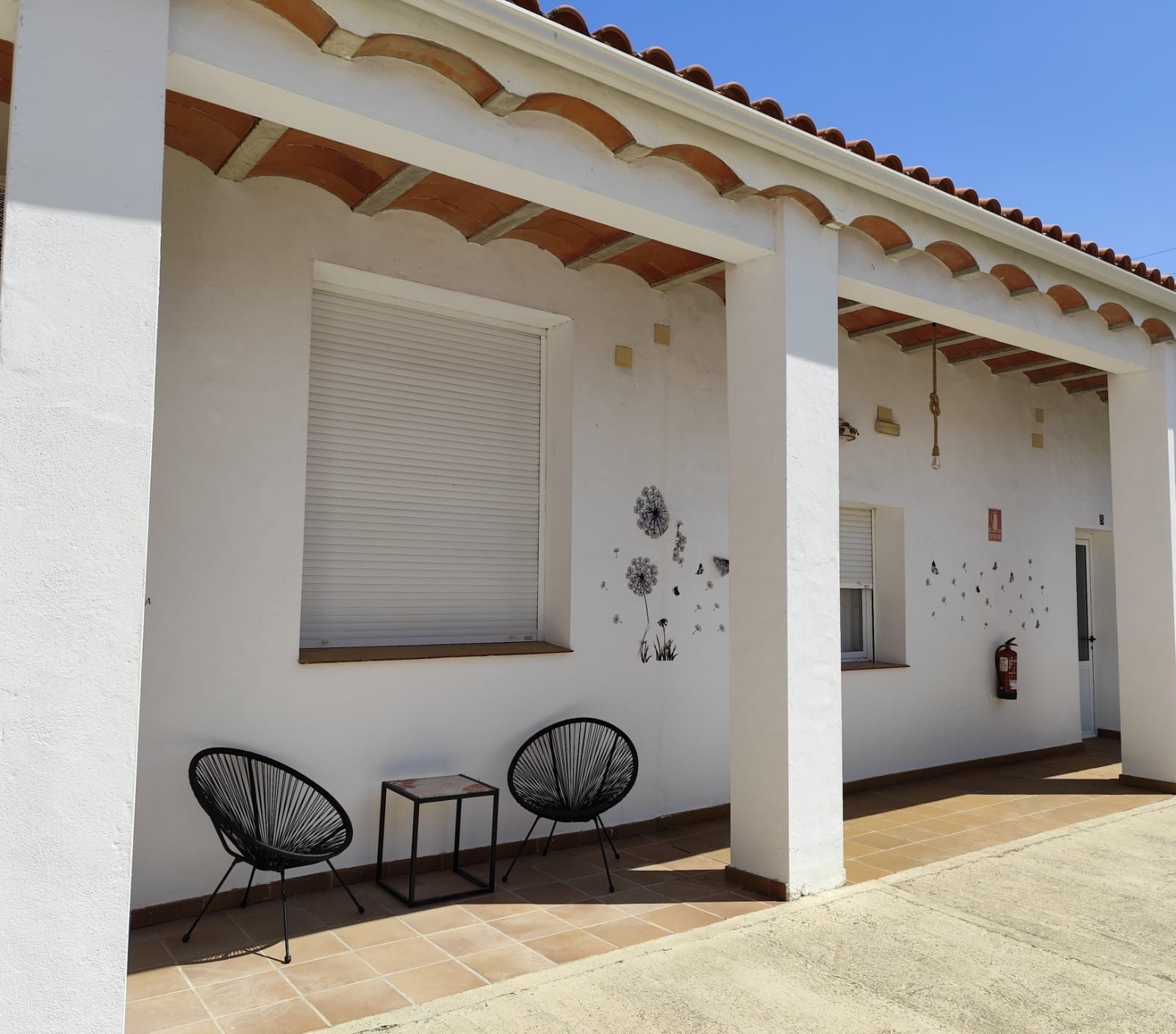Un edificio blanco con dos sillas y una mesa delante.