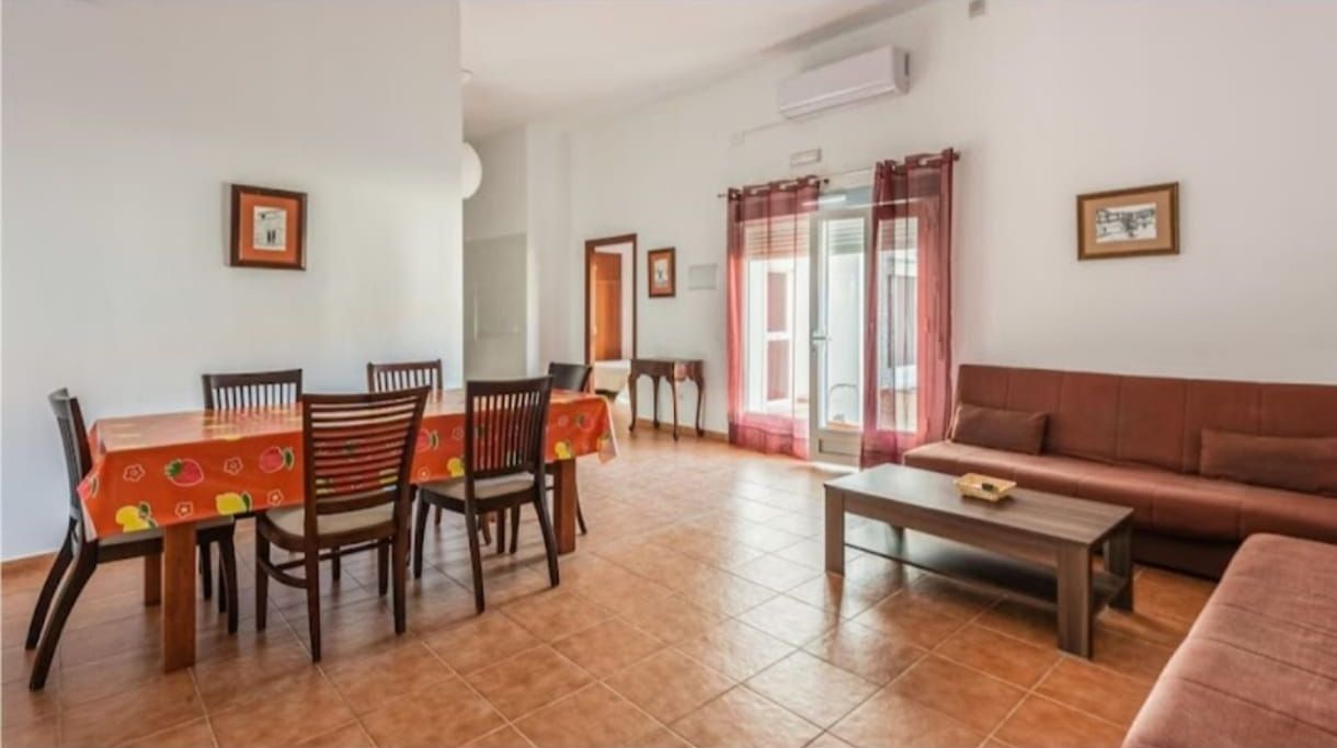 Una sala de estar con un sofá, una mesa, sillas y una mesa de café.