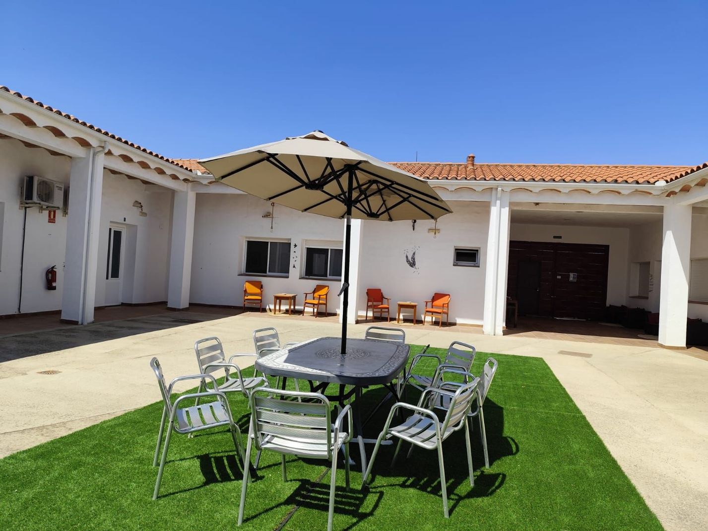 Un patio con una mesa y sillas bajo una sombrilla.