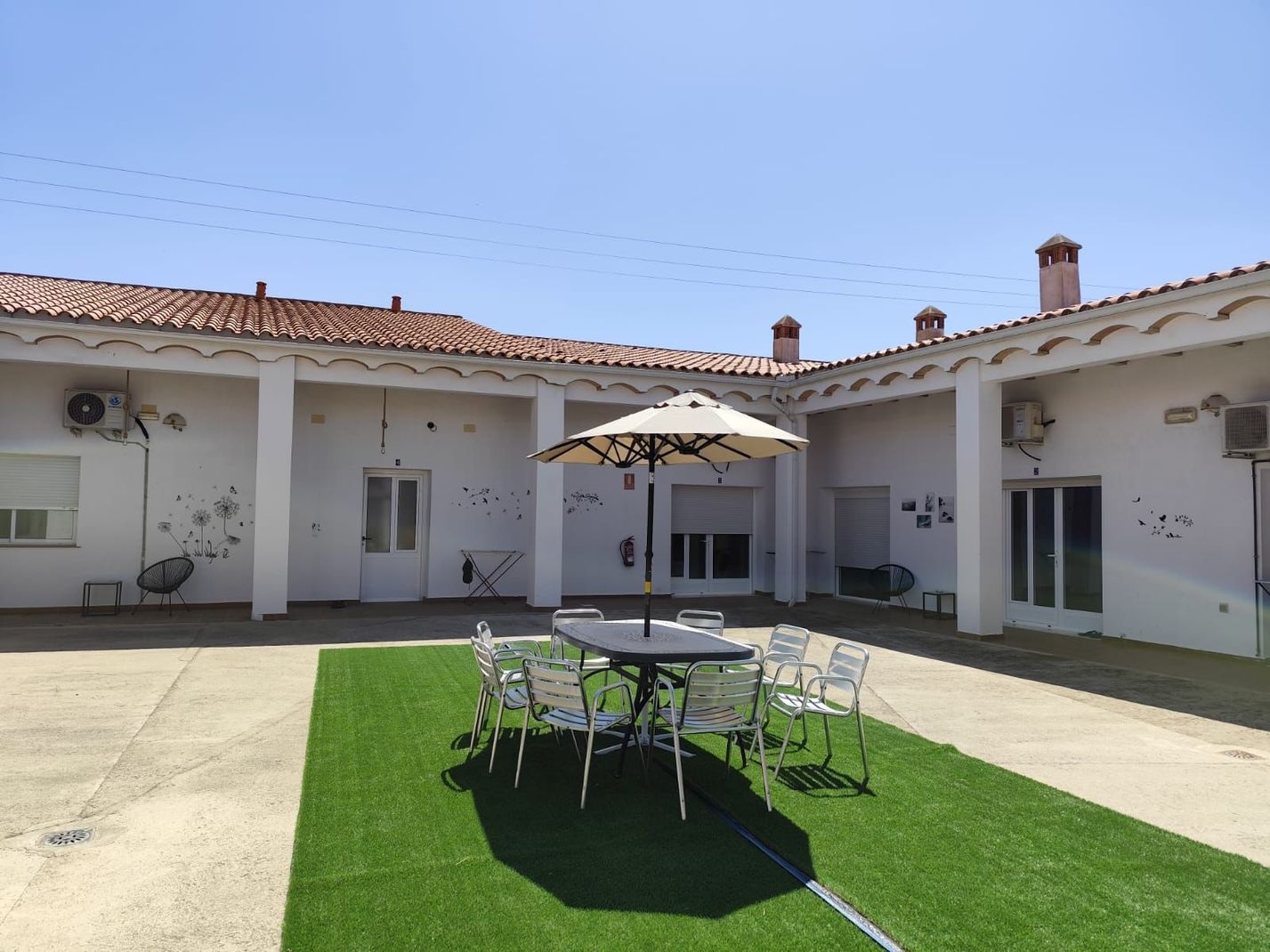 Un patio con una mesa y sillas bajo una sombrilla.