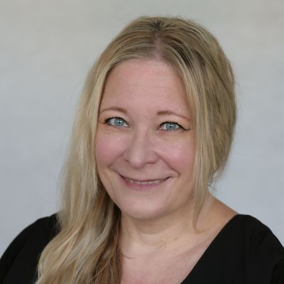 Porträt einer lächelnden blonden Frau vor grauem Hintergrund