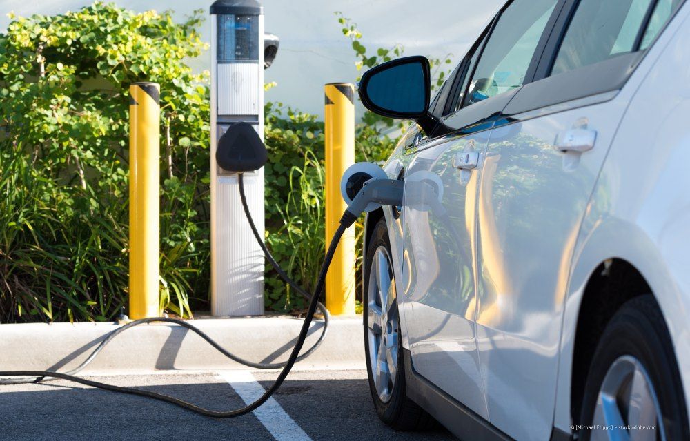 Weißes Elektroauto lädt an einer öffentlichen Ladestation im Freien
