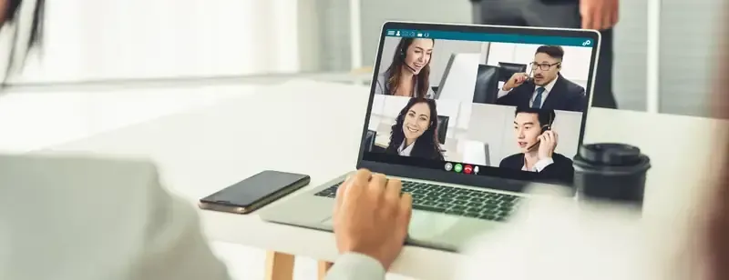 Una persona en una videoconferencia con otras cuatro personas en la pantalla de una laptop.