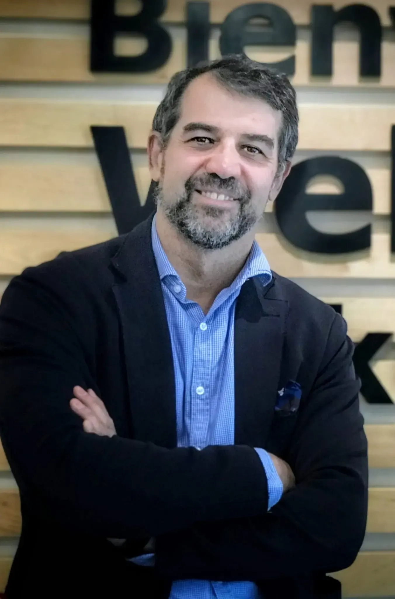 Hombre con los brazos cruzados. Lleva en los antebrazos un texto que dice 