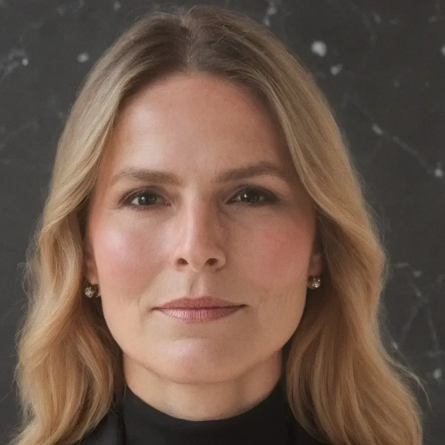 Mujer con blazer sonríe, cerca de la ventana.