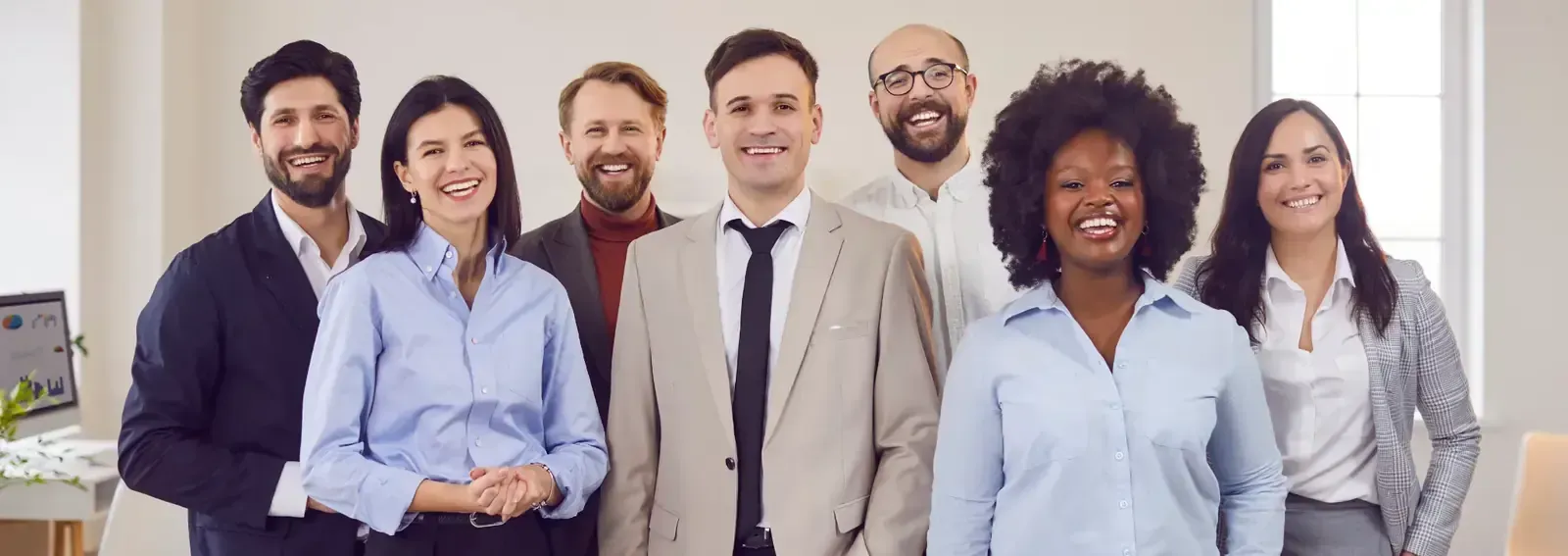 Grupo de personas sonrientes con vestimenta profesional posando en el interior.