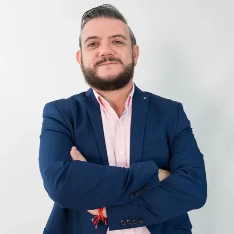 Hombre con los brazos cruzados. Lleva en los antebrazos un texto que dice 