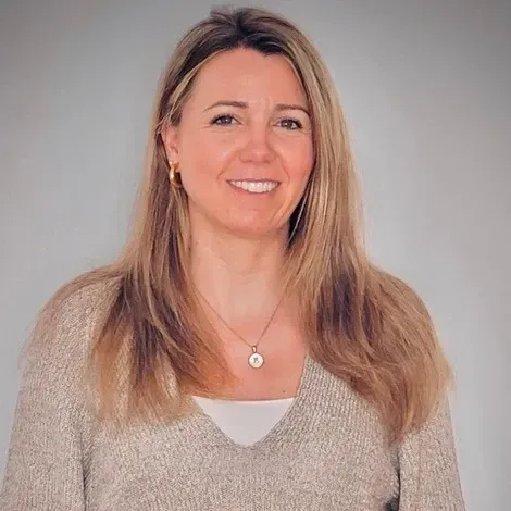 Hombre con traje oscuro, camisa blanca, corbata verde, mirando hacia adelante, expresión neutra.