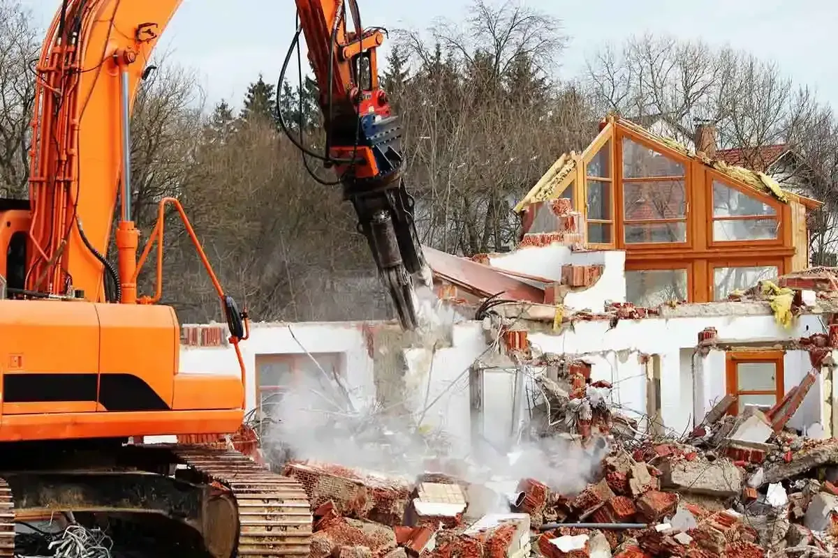 Una gran excavadora naranja está demoliendo una casa.