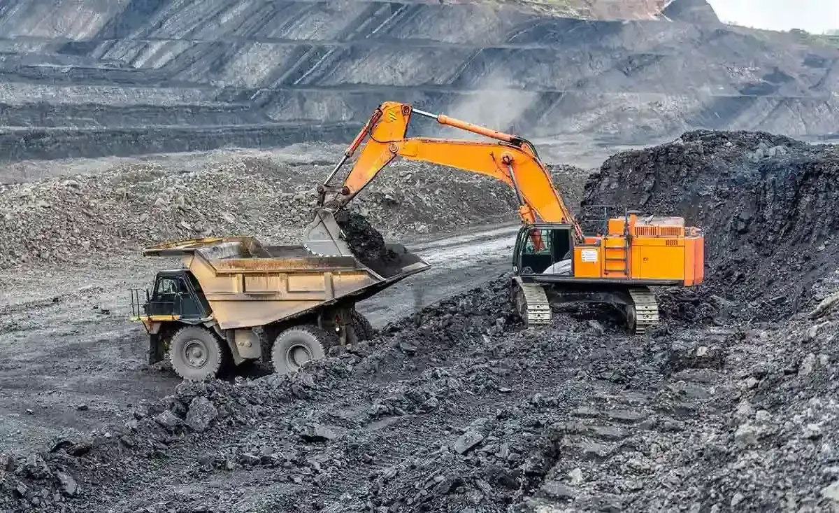 Una excavadora está cargando un camión volquete con carbón en una mina de carbón.