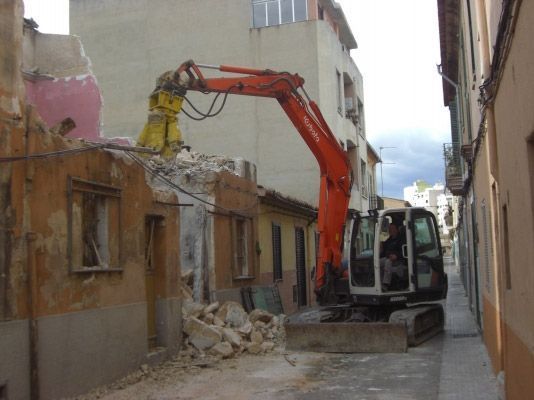 Se está utilizando una excavadora naranja para demoler un edificio.