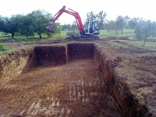Una excavadora está cavando un hoyo en la tierra de un campo.