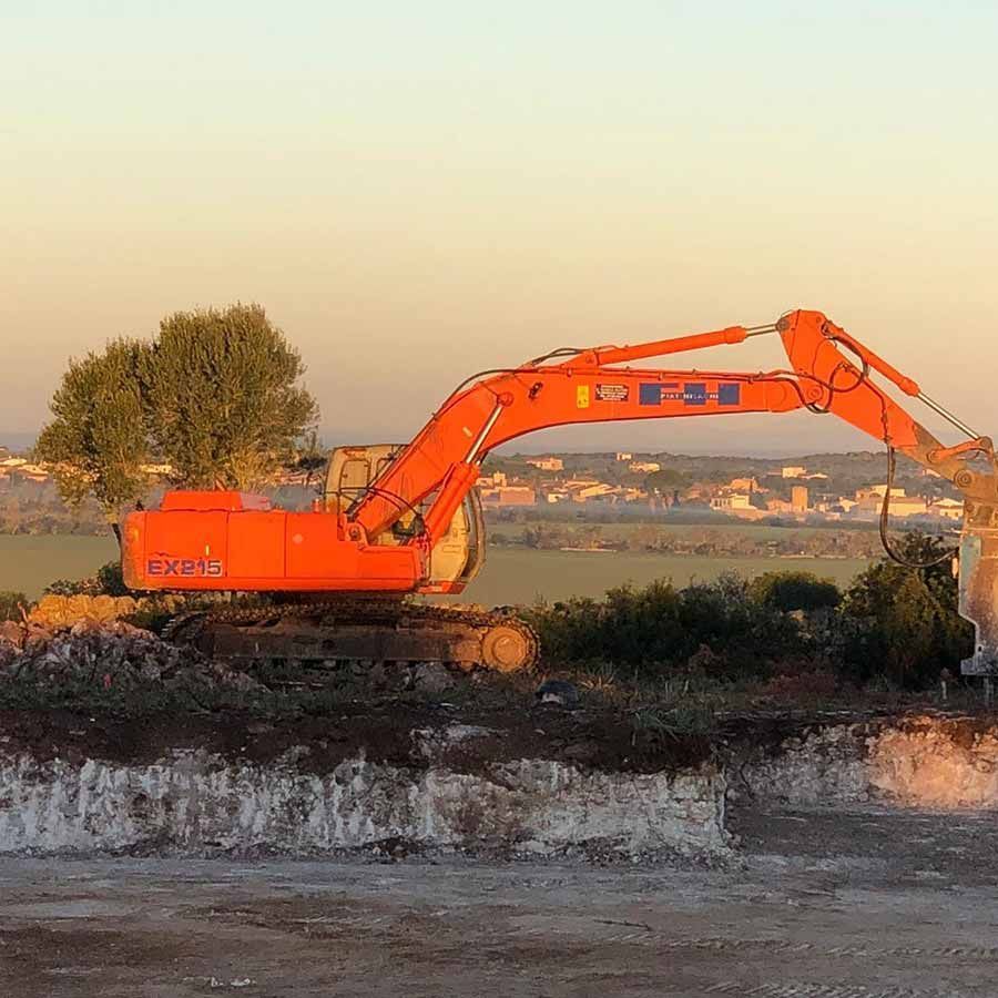 Una gran excavadora naranja está sentada encima de un campo de tierra.