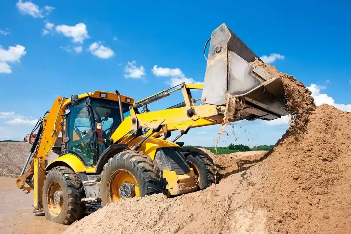 Una excavadora amarilla está cargando tierra en una pila.