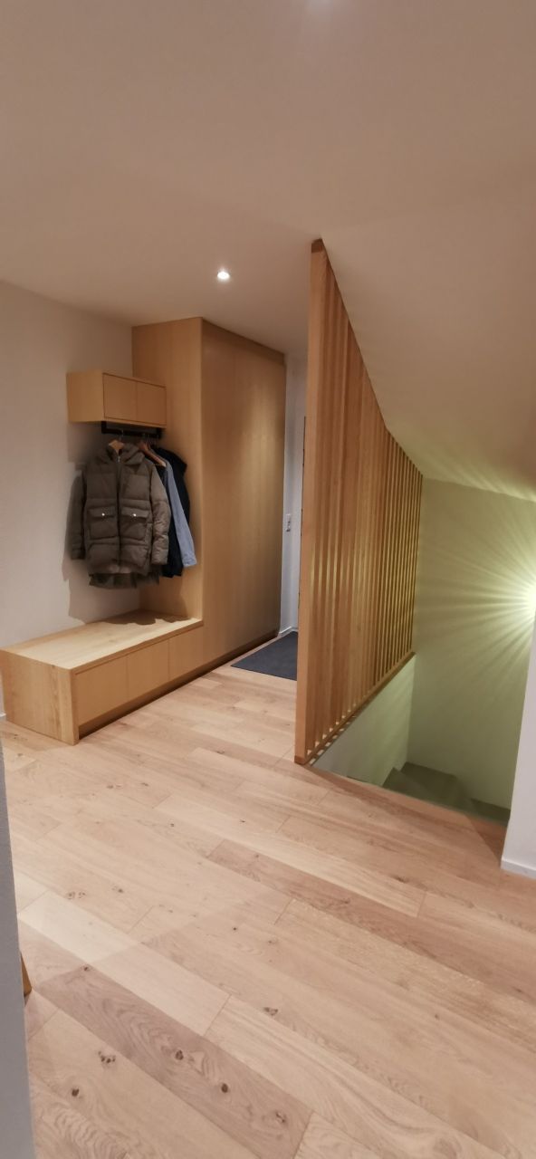 Un couloir avec parquet et escalier menant au deuxième étage.