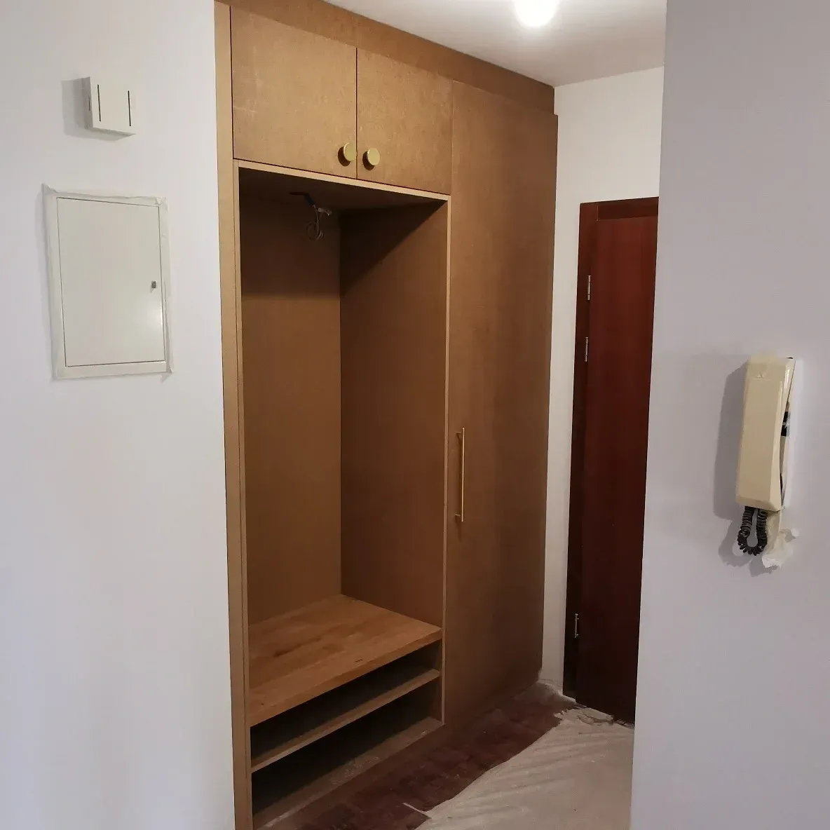 Un couloir avec une porte et un téléphone au mur