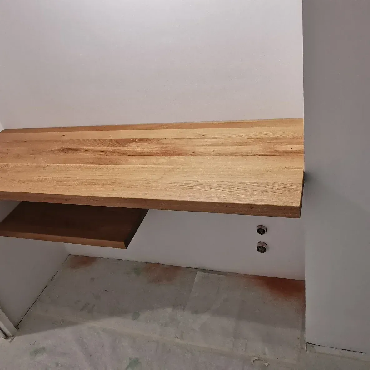 Un bureau en bois avec une étagère en dessous dans une pièce.
