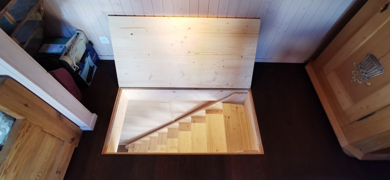 Un escalier en bois est intégré au sol d'une pièce.
