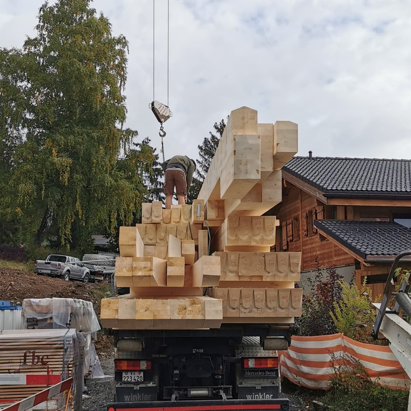 Une grue soulève une pile de poutres en bois à l'arrière d'un camion