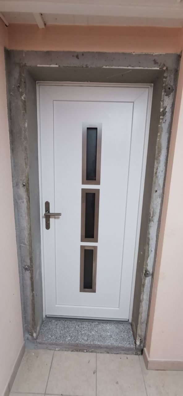 Une porte blanche avec trois fenêtres se trouve dans une pièce.