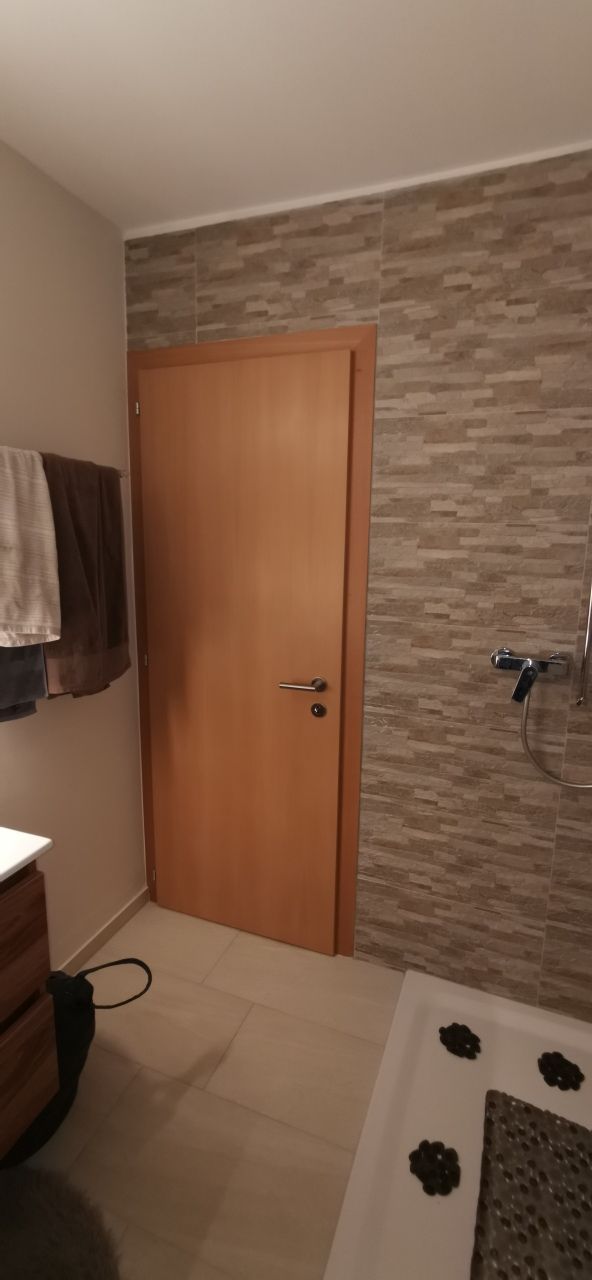 Une salle de bain avec une porte en bois et un mur en pierre