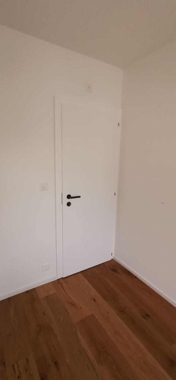 Une pièce vide avec un parquet et des murs blancs.