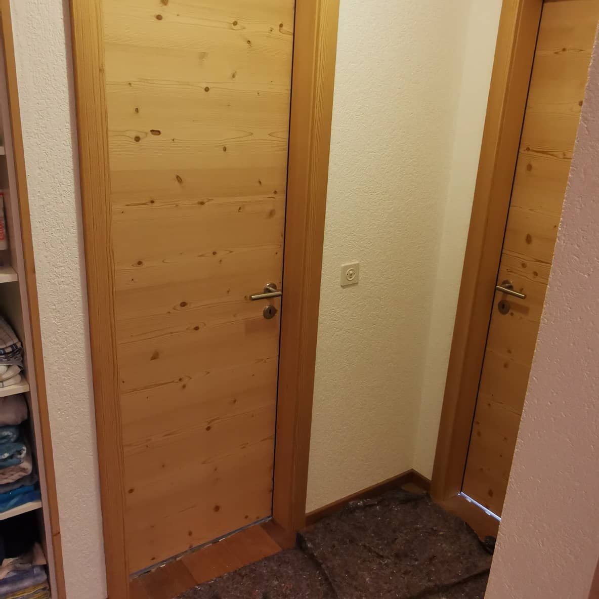 Un couloir avec deux portes en bois menant à un placard