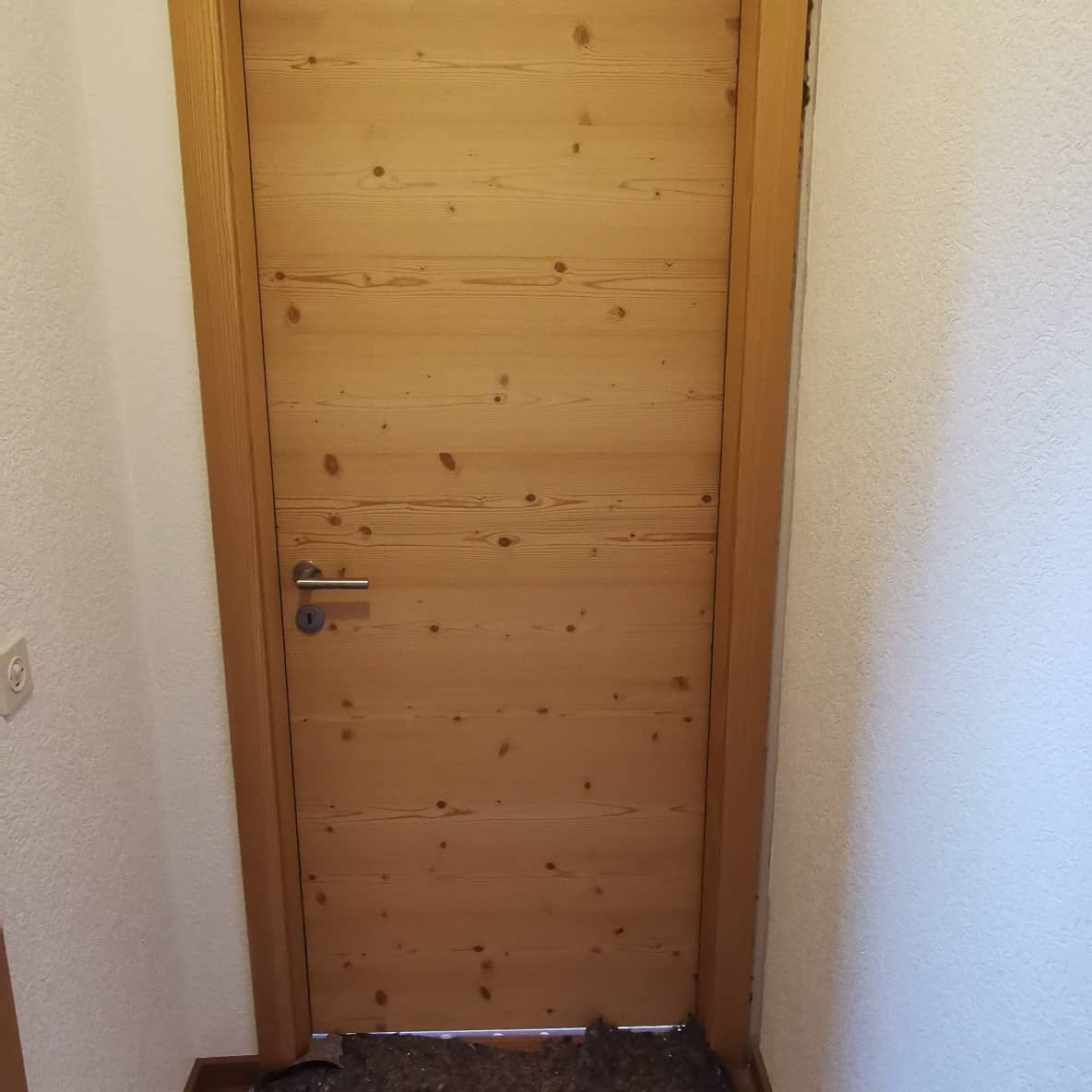 Une porte en bois dans un couloir avec un mur blanc