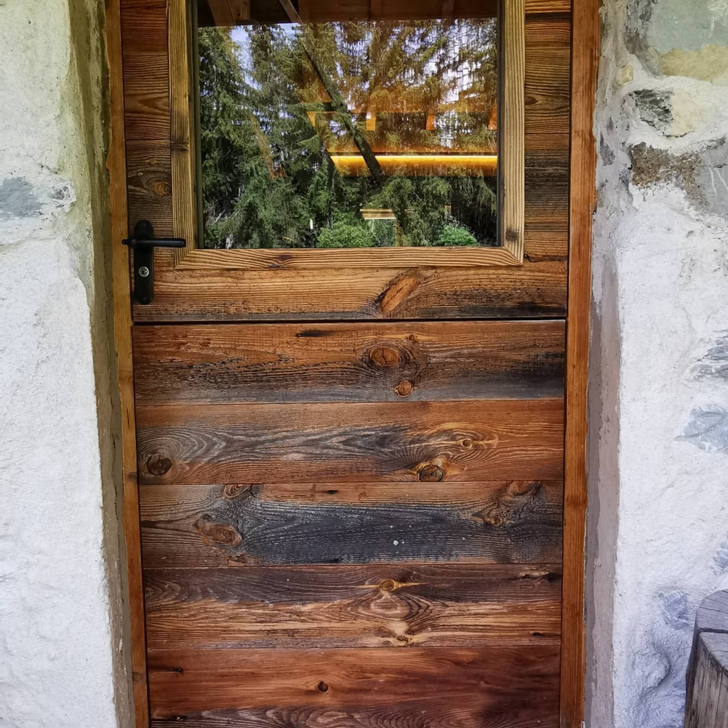 Une porte en bois avec une fenêtre et une poignée noire