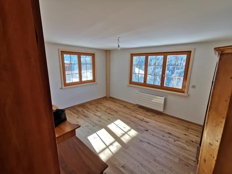 Une pièce vide avec du parquet et trois fenêtres.