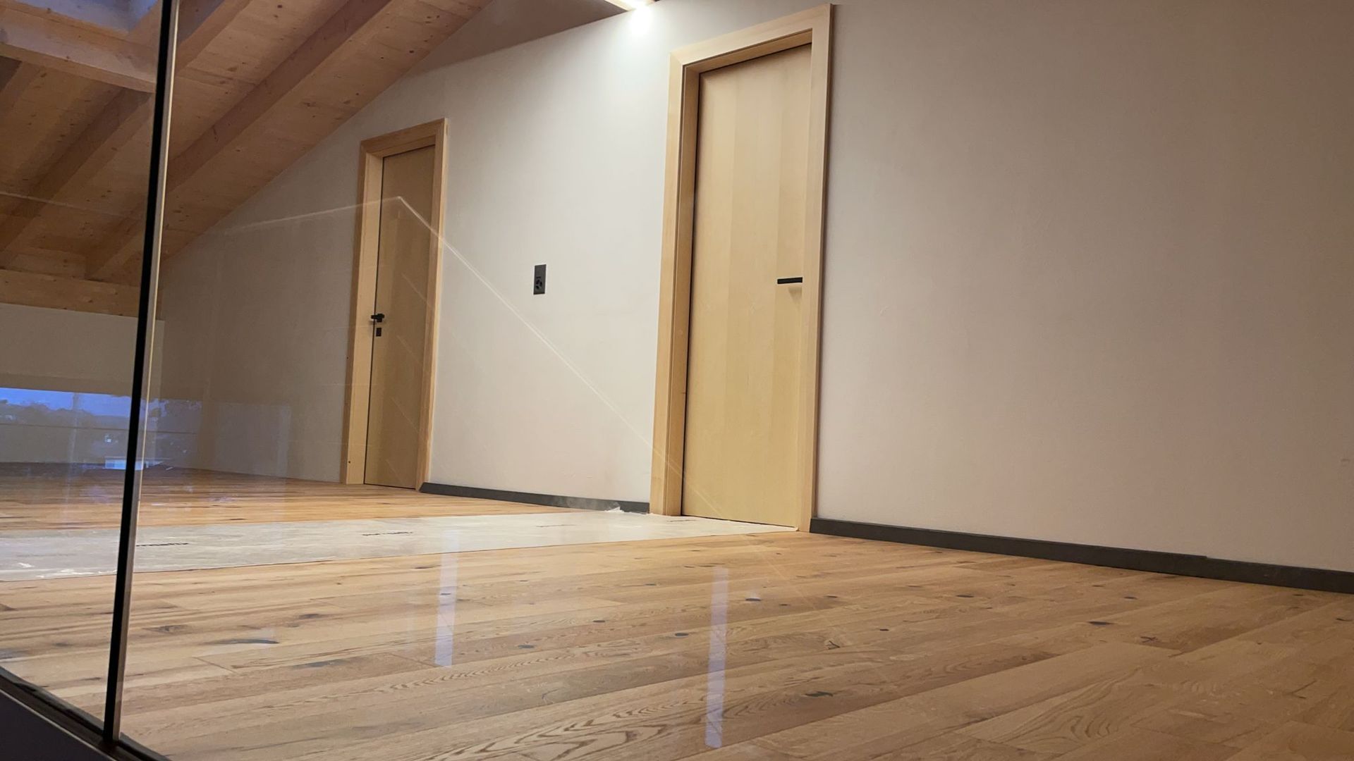 Un couloir avec parquet et garde-corps en verre.