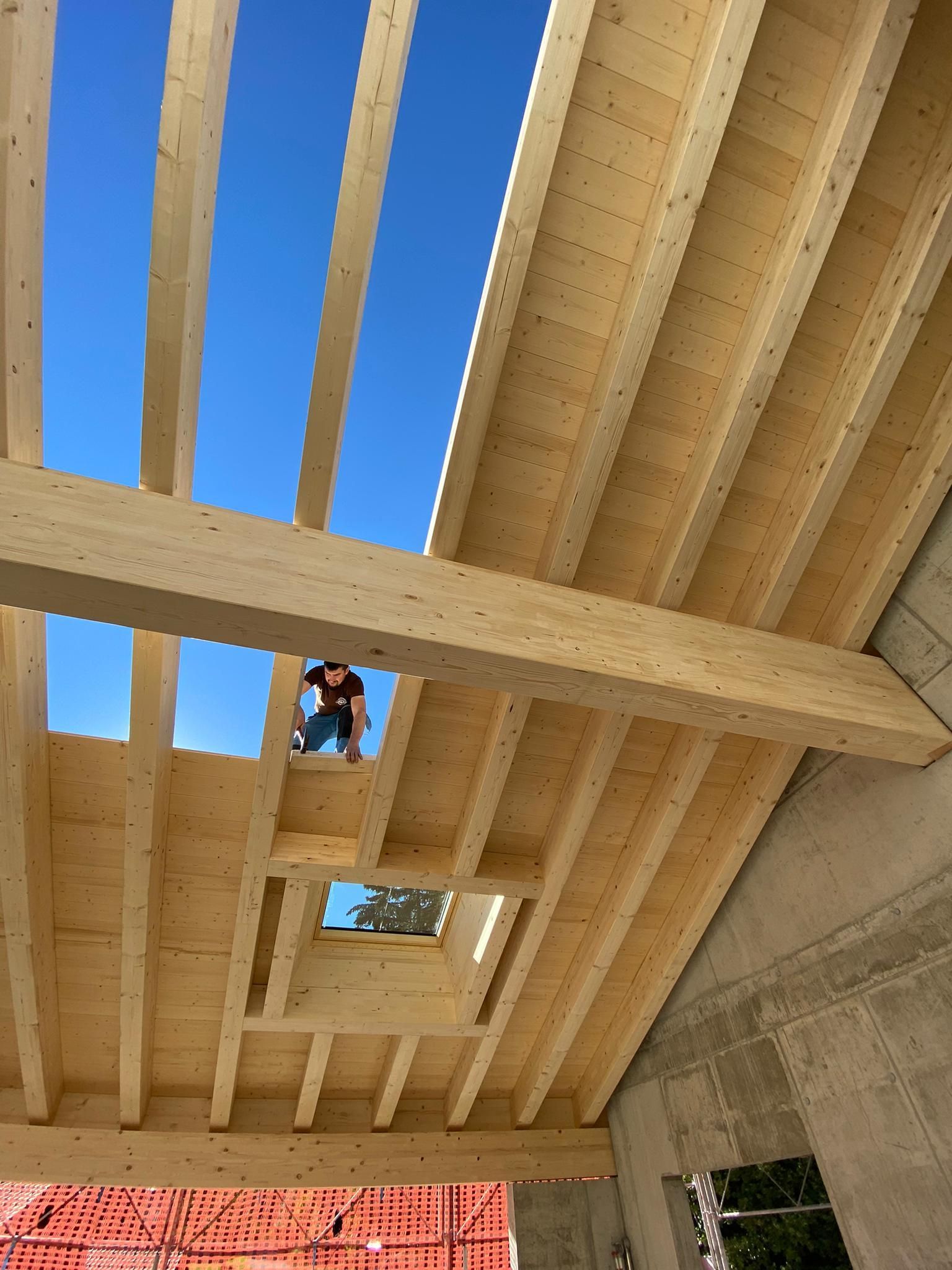 Un homme se tient au sommet d'une structure en bois et regarde le ciel.