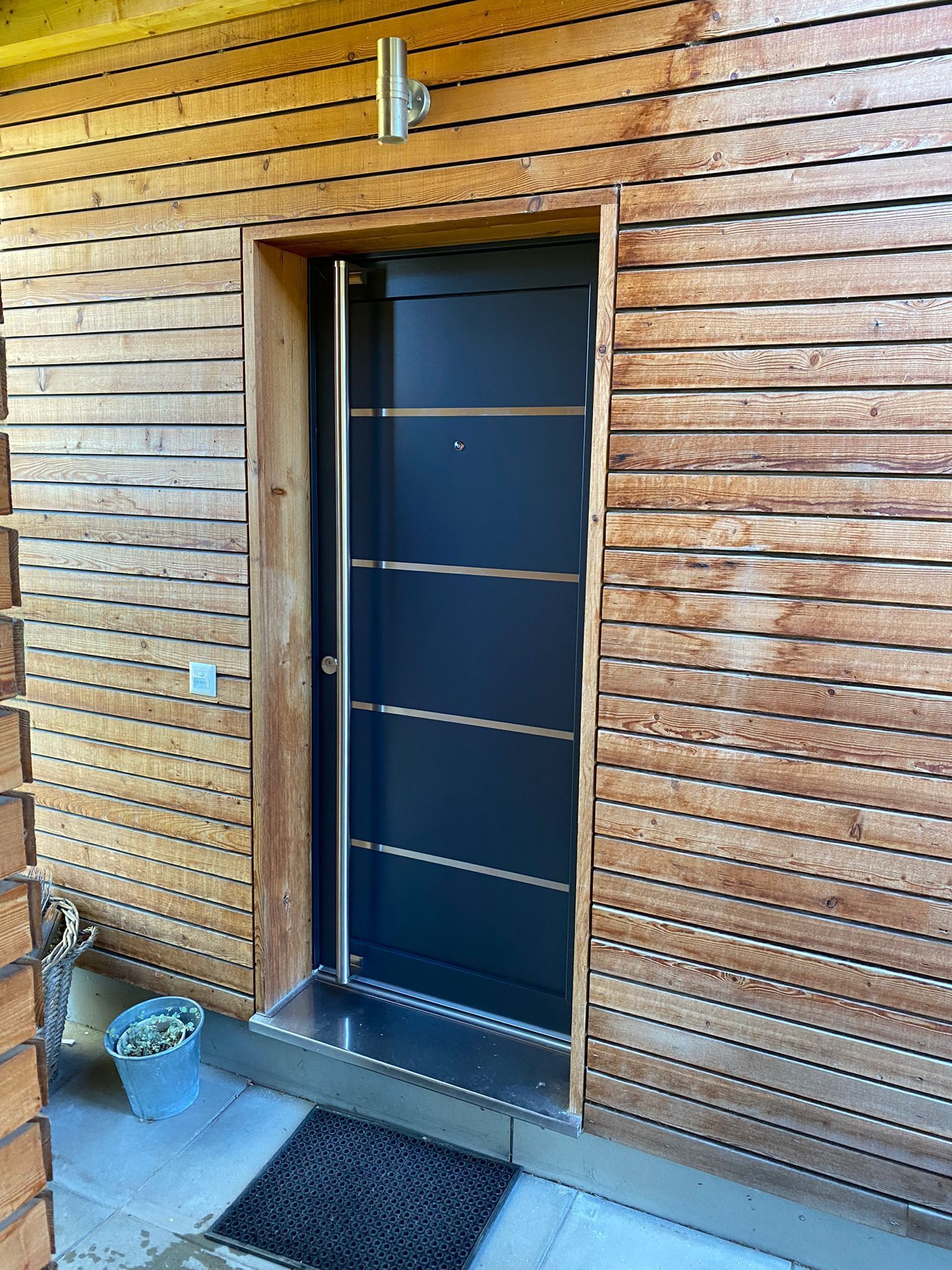 Une porte noire se trouve sur le côté d'un bâtiment en bois.