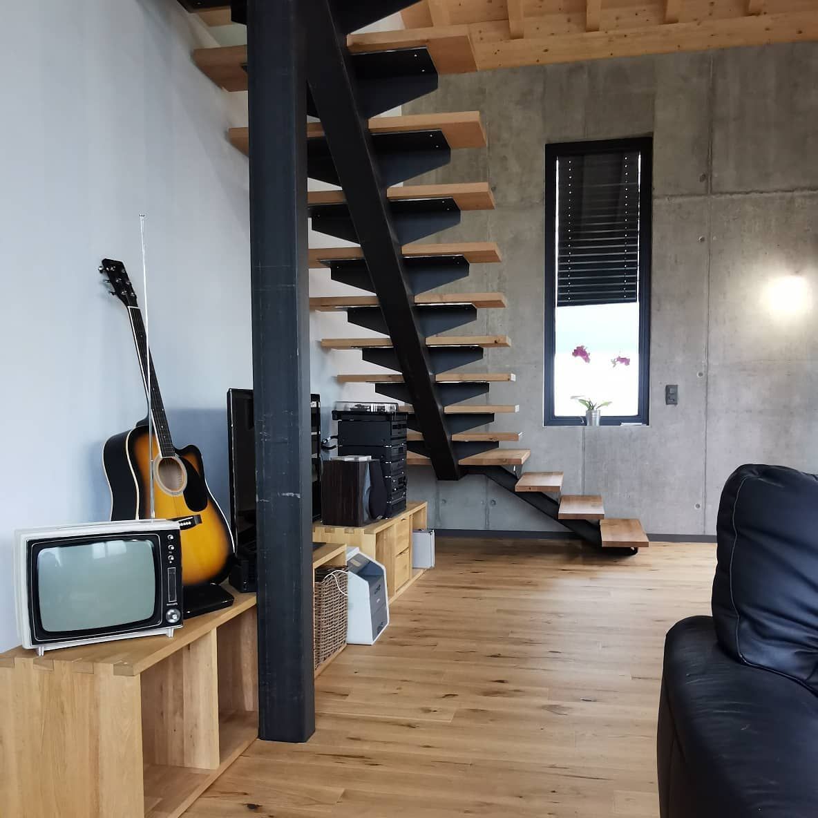 Un salon avec un escalier et une guitare sur une étagère