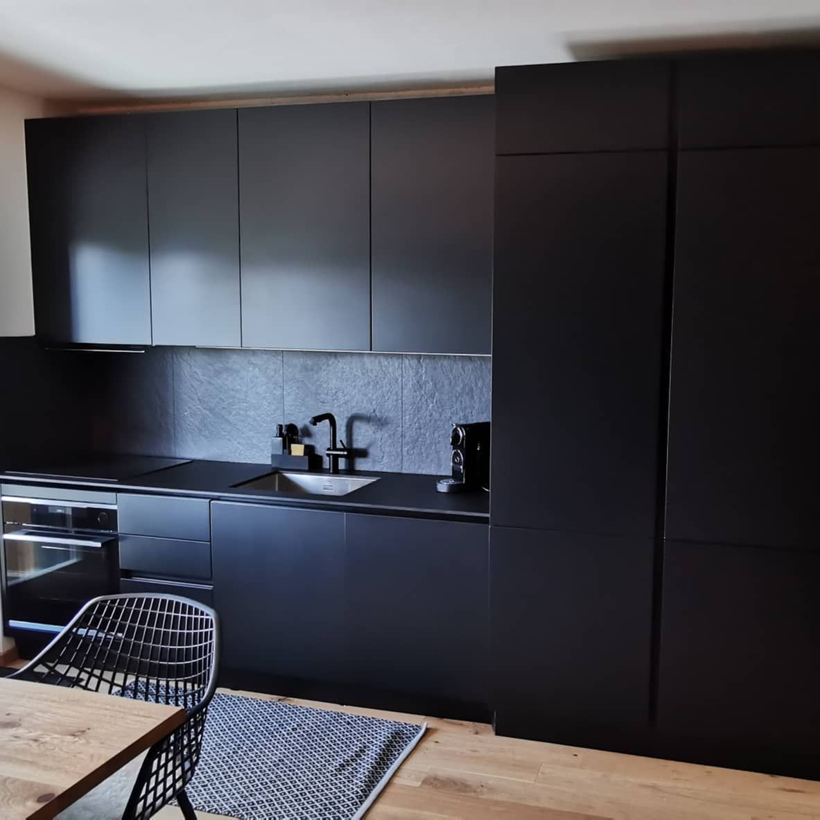 Une cuisine avec des armoires noires et une table et des chaises