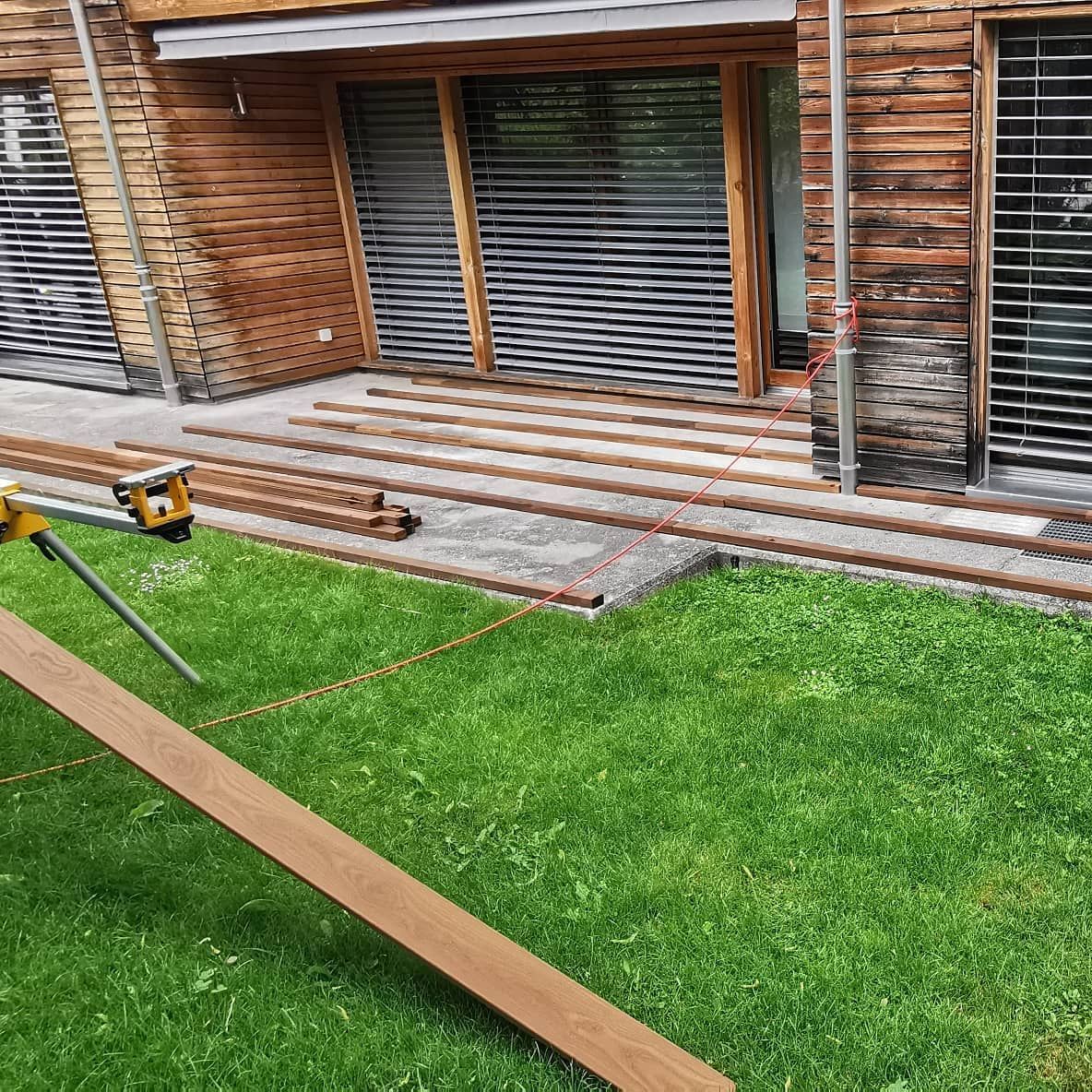 Une terrasse en bois est en cours de construction devant une maison en bois.