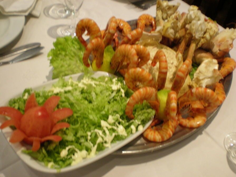 Um prato de comida com camarão e alface sobre uma mesa.