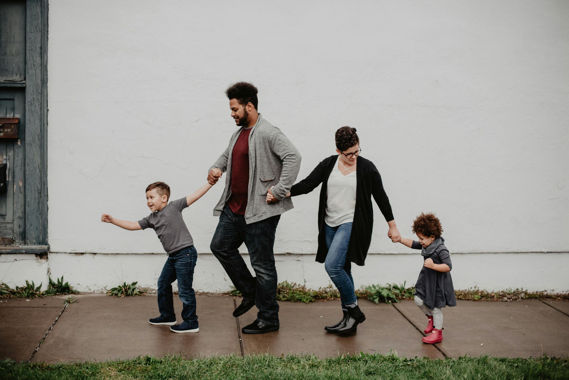 Uma família está caminhando pela calçada de mãos dadas.