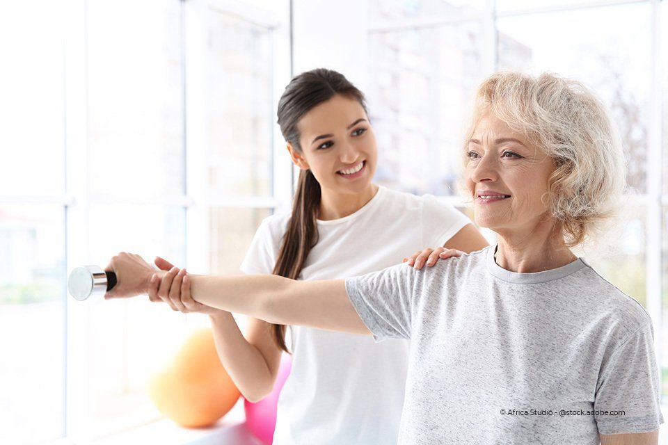 Therapeutin hilft älterer Frau bei Übungen
