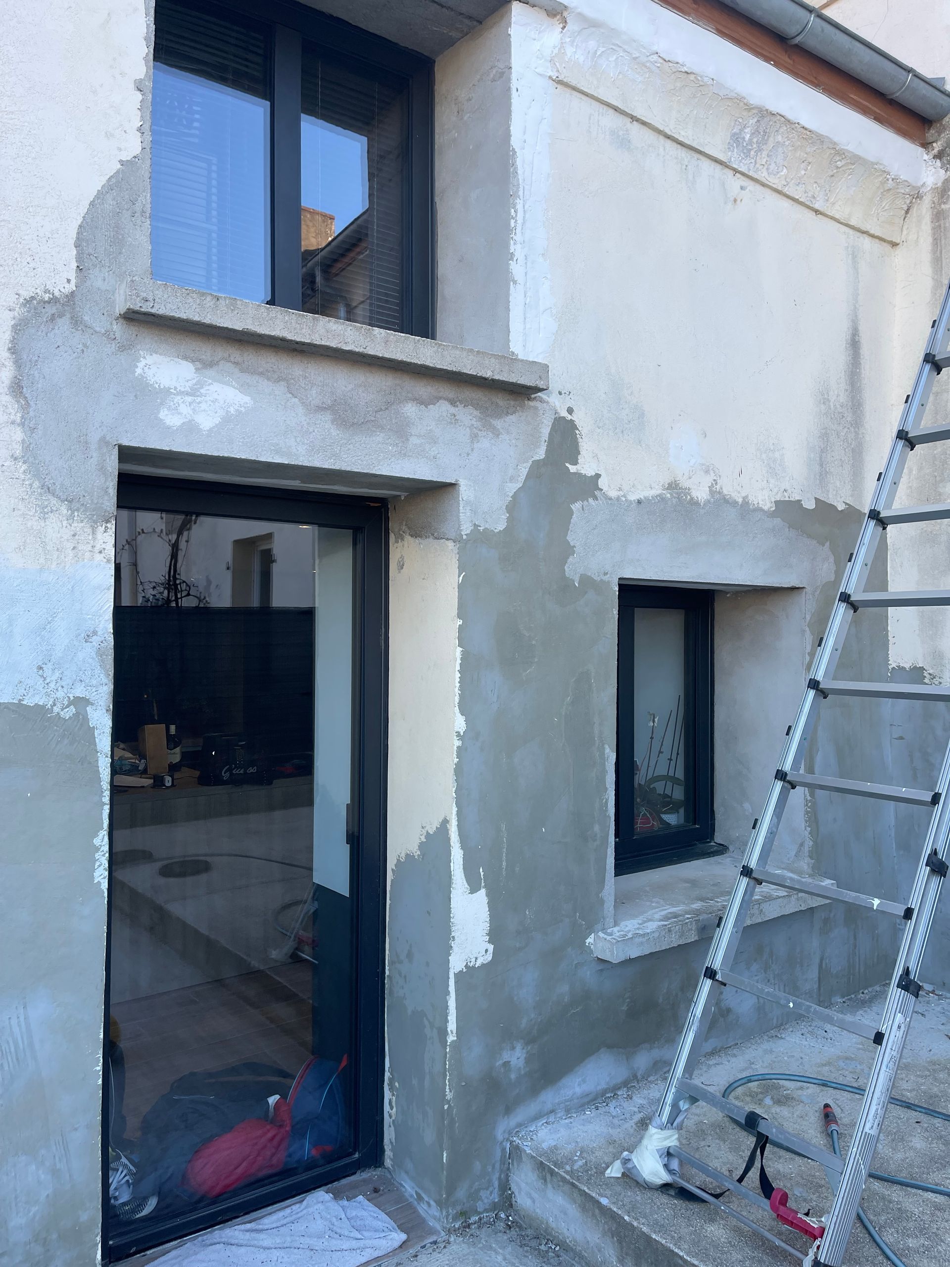 Fenêtre encastrée dans un mur en pierres apparentes avec une grille de sécurité