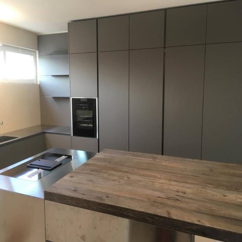 Una cucina con mobili grigi e un piano di lavoro in legno