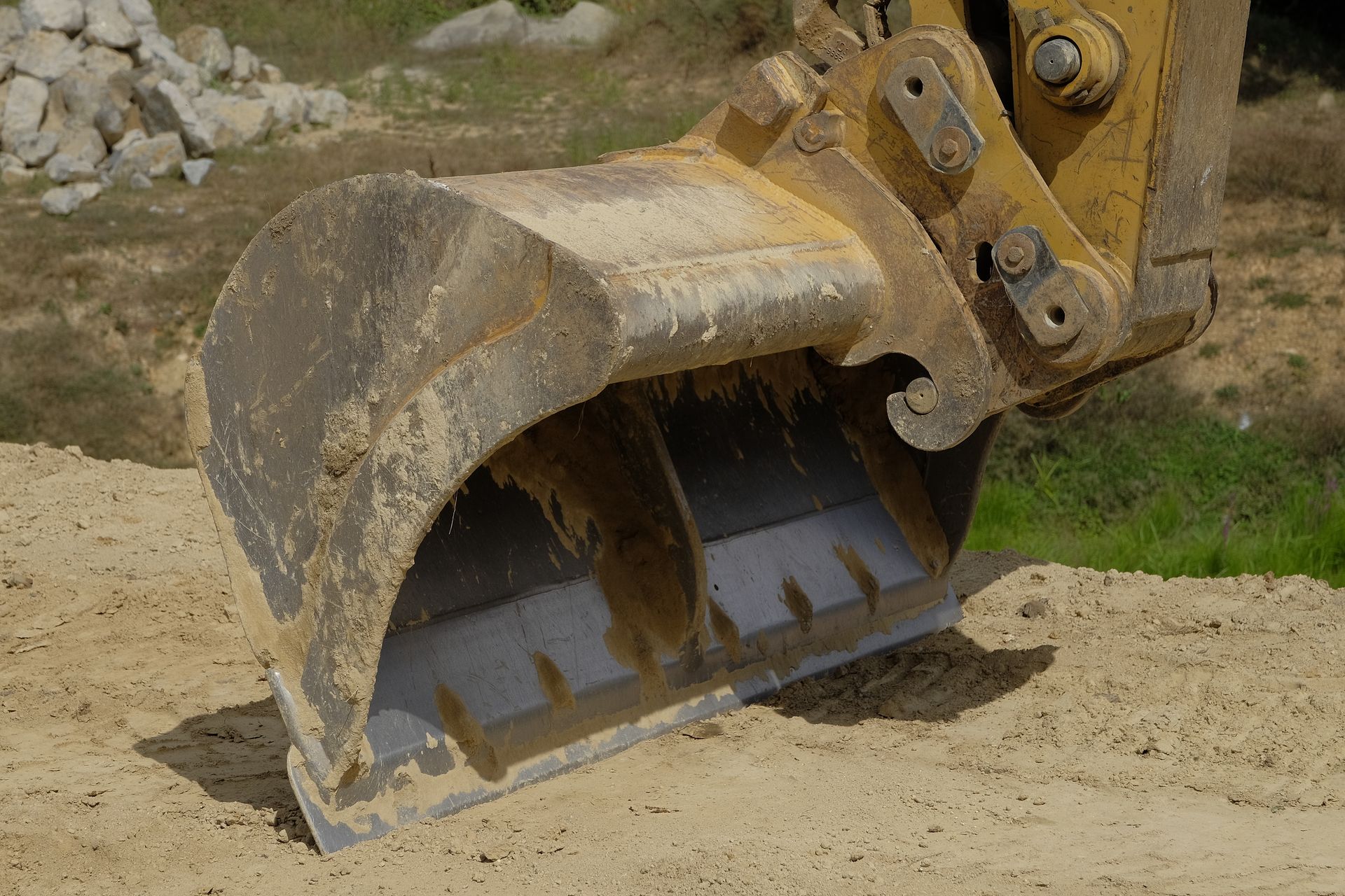 Un godet jaune d'excavatrice repose dans la terre sur un chantier de construction.