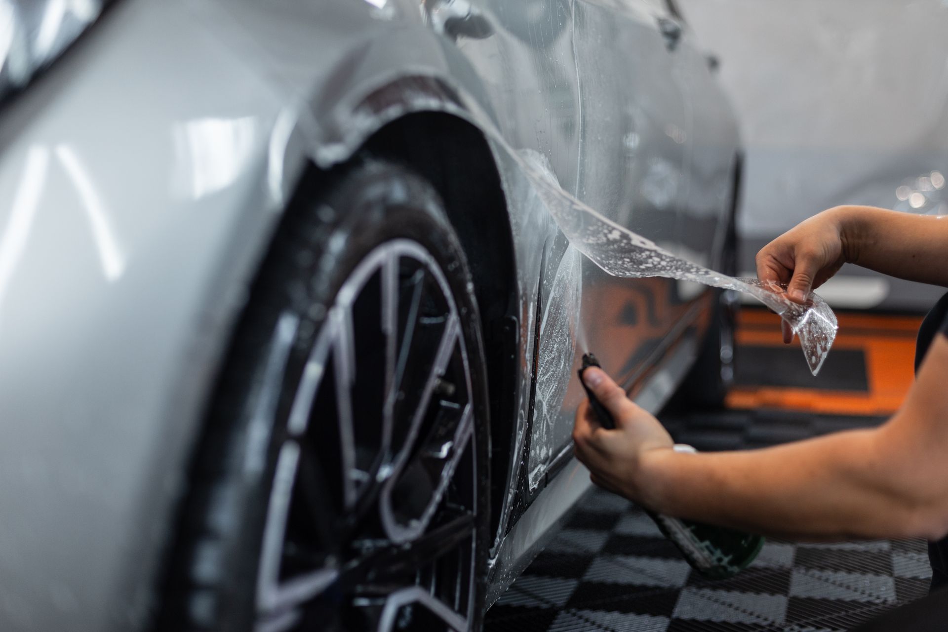 Un car detailer qui pose un PPF sur l'aile d'une voiture.