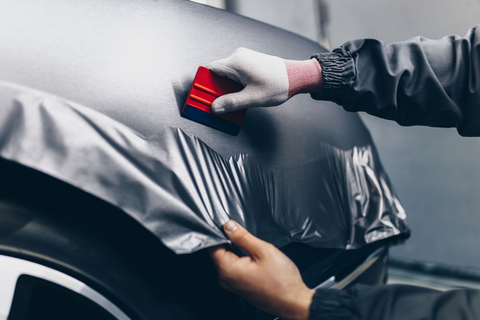 Un car detailer qui applique un covering mat sur la carrosserie d'une voiture.