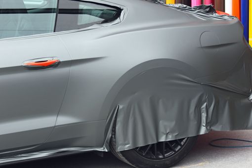 Un covering gris posé sur une voiture.