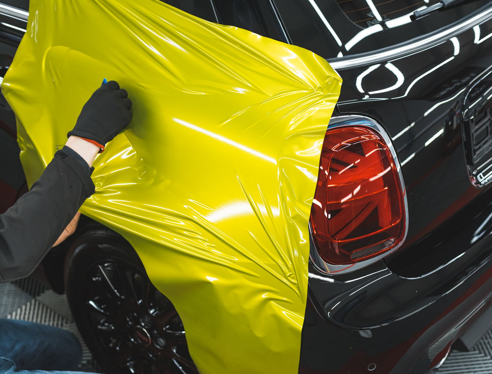 Pose d'un covering jaune sur une voiture noire.