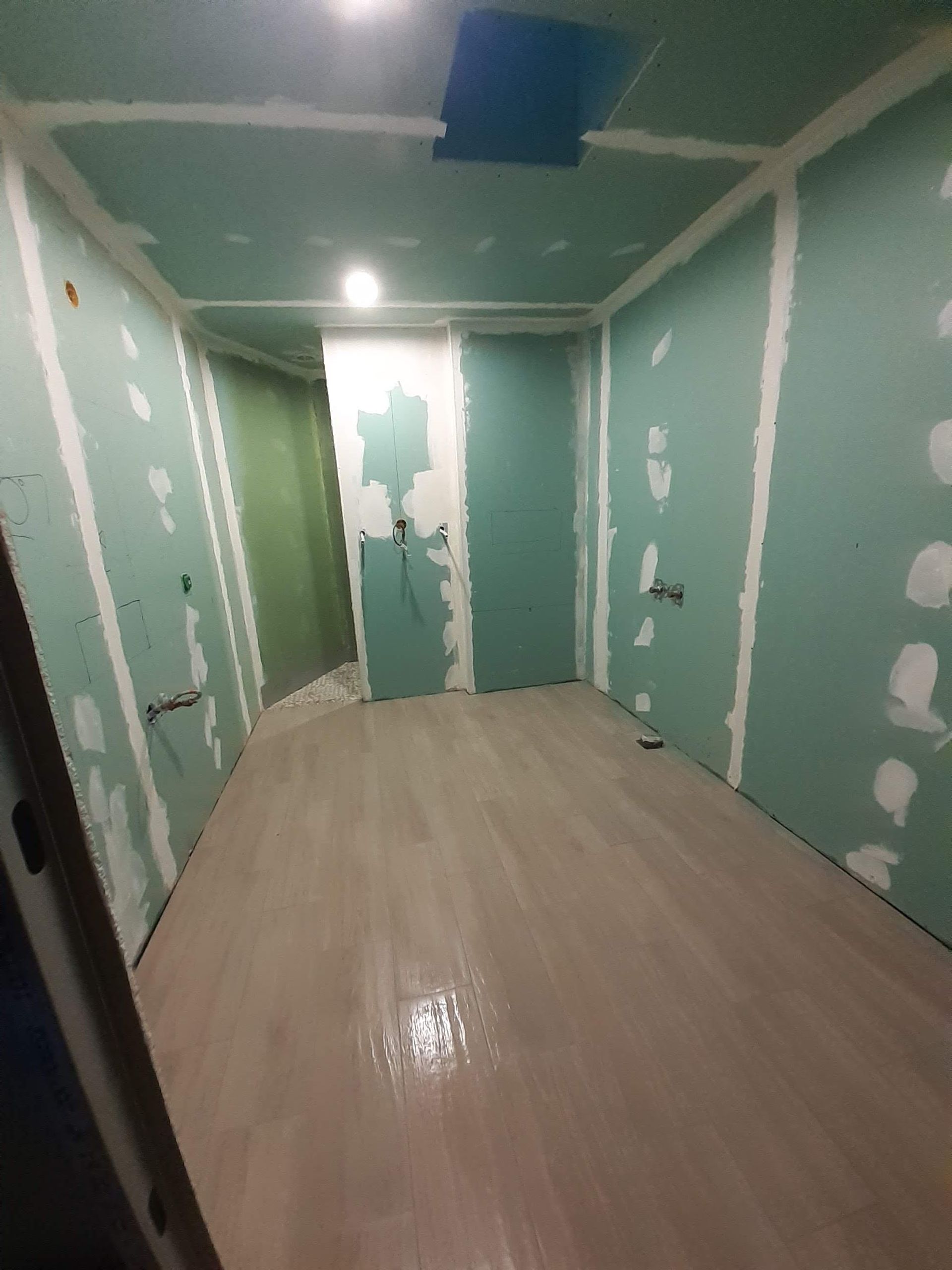 Une pièce vide avec du papier peint qui se décolle et une fenêtre.