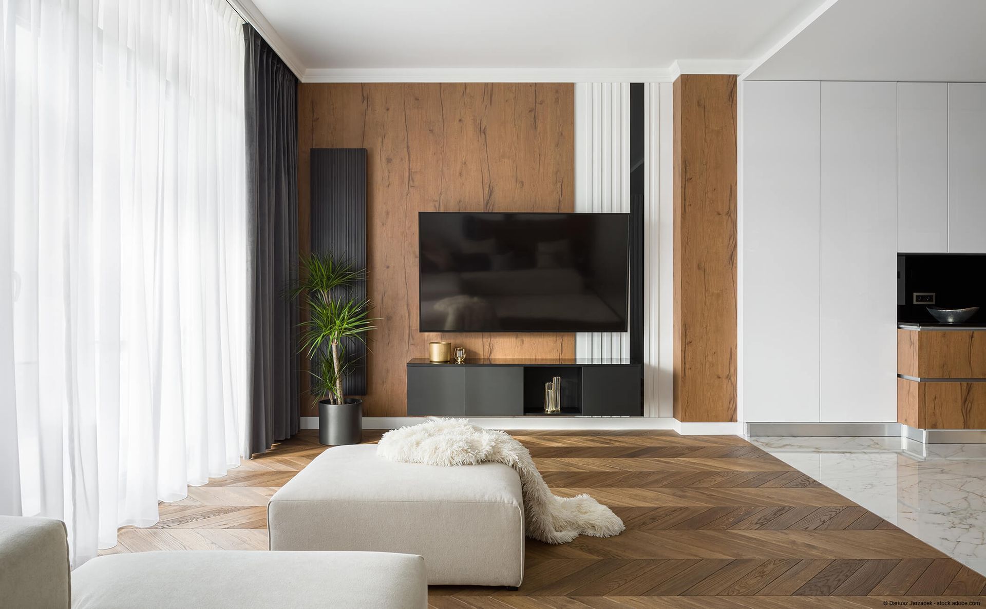 Ein modernes Wohnzimmer mit holzgetäfelten Wänden, einem Fernseher und einer schwarzen Konsole auf Holzboden.