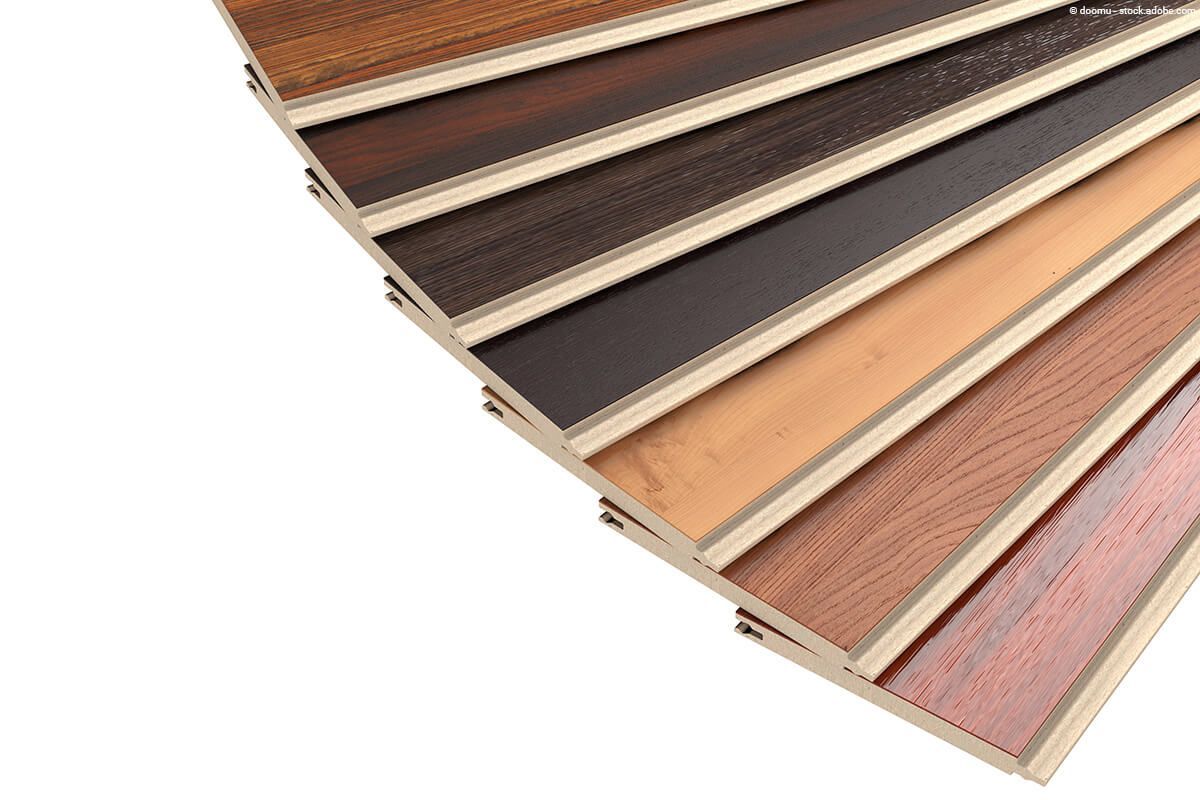 Eine fächerförmige Präsentation verschiedener Laminatdielen in Holzoptik, deren Farbtöne von hell bis dunkel reichen.